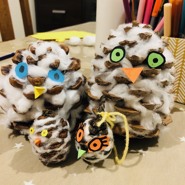 Four fluffy owls made out of pinecones and cotton wool.